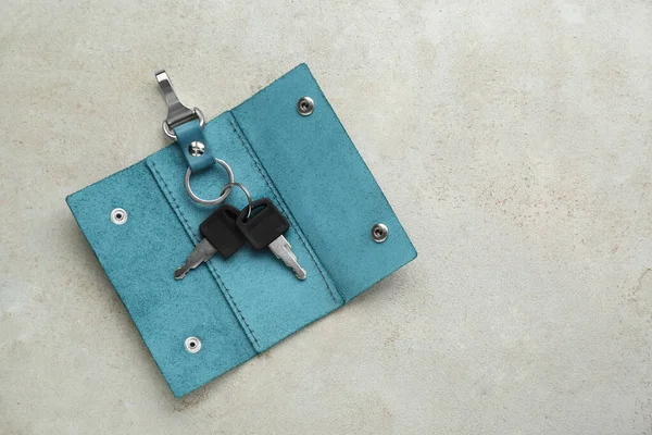 Stylish leather holder with keys on light grey table, top view. Space for text