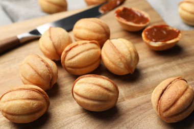 Homemade walnut shaped cookies with boiled condensed milk on wooden board, closeup