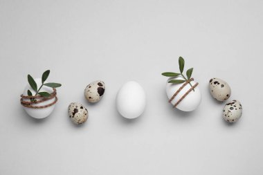 Beautifully decorated Easter eggs on light grey background, flat lay
