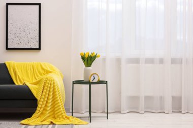 Spring atmosphere. Stylish living room interior with comfortable furniture and bouquet of beautiful yellow tulips