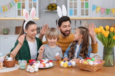 Mutlu bir aile mutfakta paskalya yumurtası boyuyor.