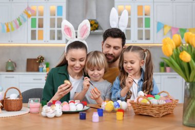 Mutlu bir aile mutfakta paskalya yumurtası boyuyor.