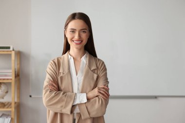 Sınıftaki beyaz tahtada genç ve mutlu bir öğretmen. Metin için boşluk