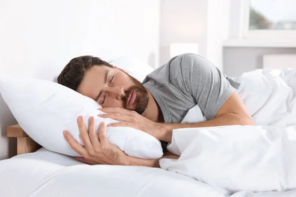 Man sleeping on comfortable pillows in bed at home