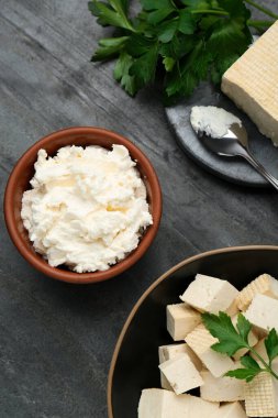 Delicious tofu cheese and parsley on black table, flat lay
