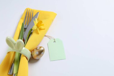 Cutlery set, Easter egg and narcissus on white background, space for text. Festive table setting