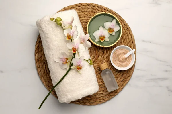 Composition with different spa products and flowers on white marble table, top view