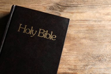 Bible on wooden table, top view with space for text. Christian religious book