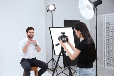 Professional photographer working with handsome model in modern photo studio
