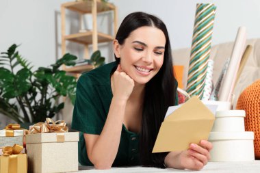 Happy woman reading greeting card on floor in living room