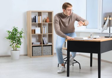 Emotional young man checking time in office. Being late