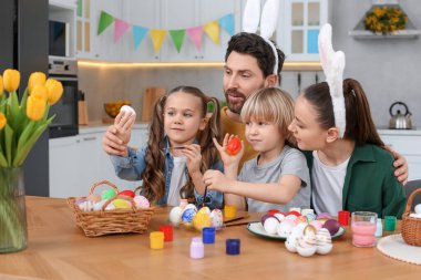 Mutlu bir aile mutfakta paskalya yumurtası boyuyor.