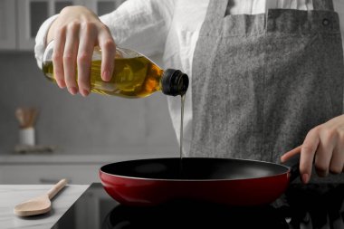 Kadın yemek yağını şişeden tavaya döküyor, yakın plan.