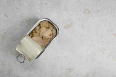 Open tin can of tasty cod liver on textured table, top view. Space for text