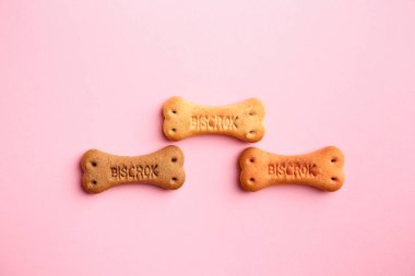 Bone shaped dog cookies on pink background, flat lay