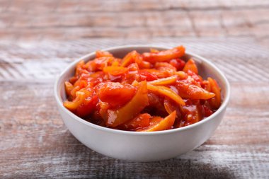 Bowl of delicious lecho on wooden table, closeup