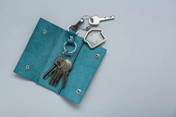 Open leather holder with keys on light grey background, top view. Space for text