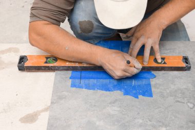 Worker making holes for bathroom water pipes in tile indoors, closeup