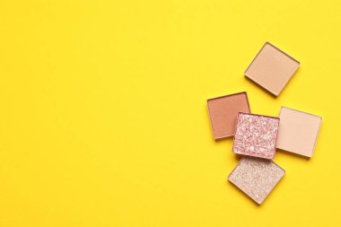 Beautiful eye shadow refill pans on yellow background, flat lay. Space for text