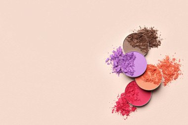Different crushed eye shadows on beige background, flat lay. Space for text