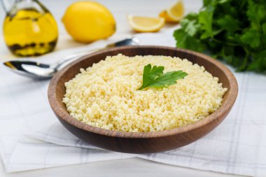 Tasty couscous with parsley on white wooden table, closeup