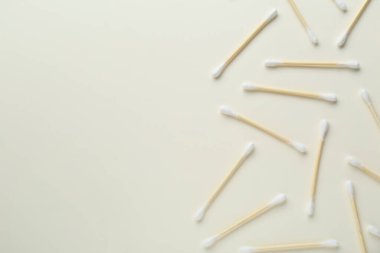 Many wooden cotton buds on beige background, flat lay. Space for text