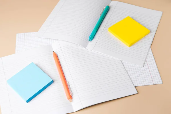 Copybooks with erasable pens and paper notes on beige background