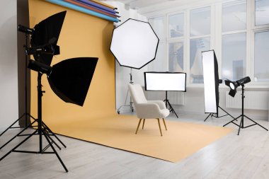 Interior of modern photo studio with armchair and professional lighting equipment