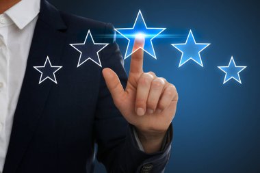 Quality rating. Man pointing at stars on virtual screen against blue background, closeup