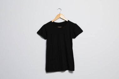 Hanger with black t-shirt on light wall. Mockup for design