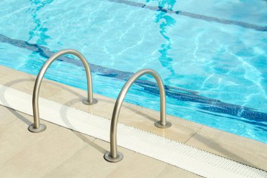 Ladder with handrails in outdoor swimming pool