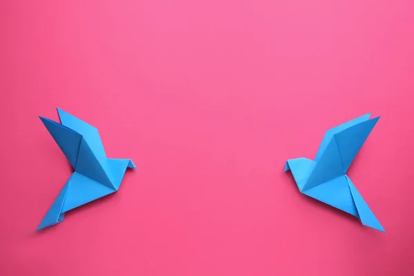 Beautiful light blue origami birds on pink background, flat lay. Space for text