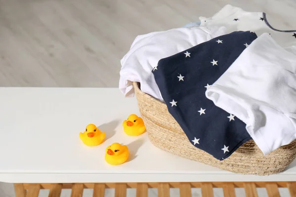 Laundry basket with baby clothes and rubber ducks on table in bathroom, closeup. Space for text