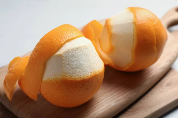 Peeled fresh oranges with zest preparing for drying on white table, closeup