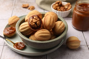 Delicious nut shaped cookies with boiled condensed milk on light textured table, closeup