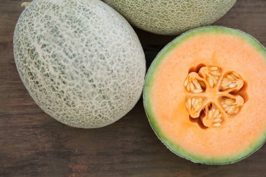 Whole and cut fresh ripe melons on wooden table, flat lay