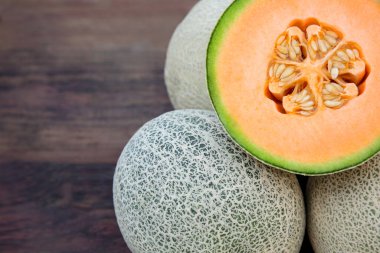 Whole and cut fresh ripe melons on wooden table, closeup. Space for text