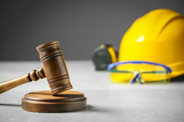 Construction and land law concepts. Judge gavel, tape measure with hardhat on light grey table, space for text