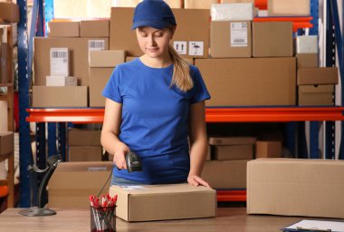 Post office worker with scanner reading parcel barcode at counter