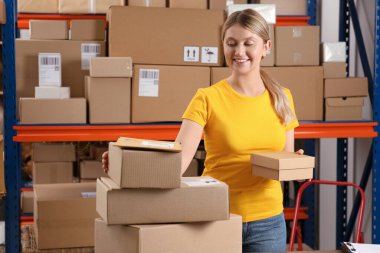Post office worker with parcels near rack indoors