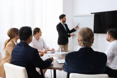 Business conference. Group of people listening to speaker report near tv screen in meeting room