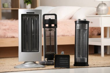 Different modern infrared heater on floor in cozy room