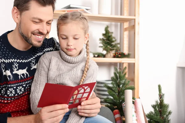 Happy man receiving greeting card from his daughter at home