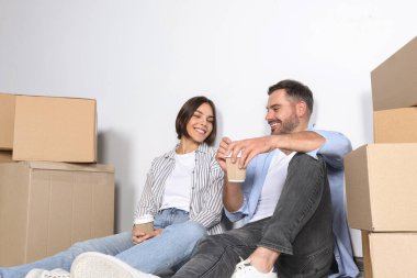 Yeni dairede kahve içip yerde dinlenen mutlu bir çift. Taşınma günü