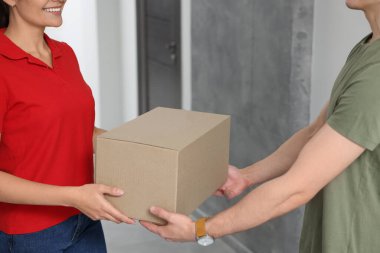 Kurye koridordaki müşteriye paket veriyor, yakın plan.