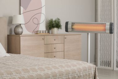 Modern electric infrared heater in cozy bedroom