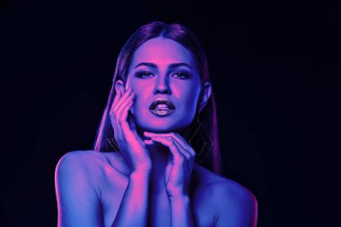 Portrait of beautiful woman posing in neon lights against black background