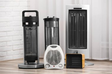 Different modern electric heaters on floor in room