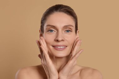 Woman massaging her face on beige background