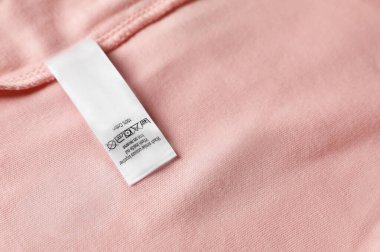 Clothing label on beautiful pink garment, top view. Space for text